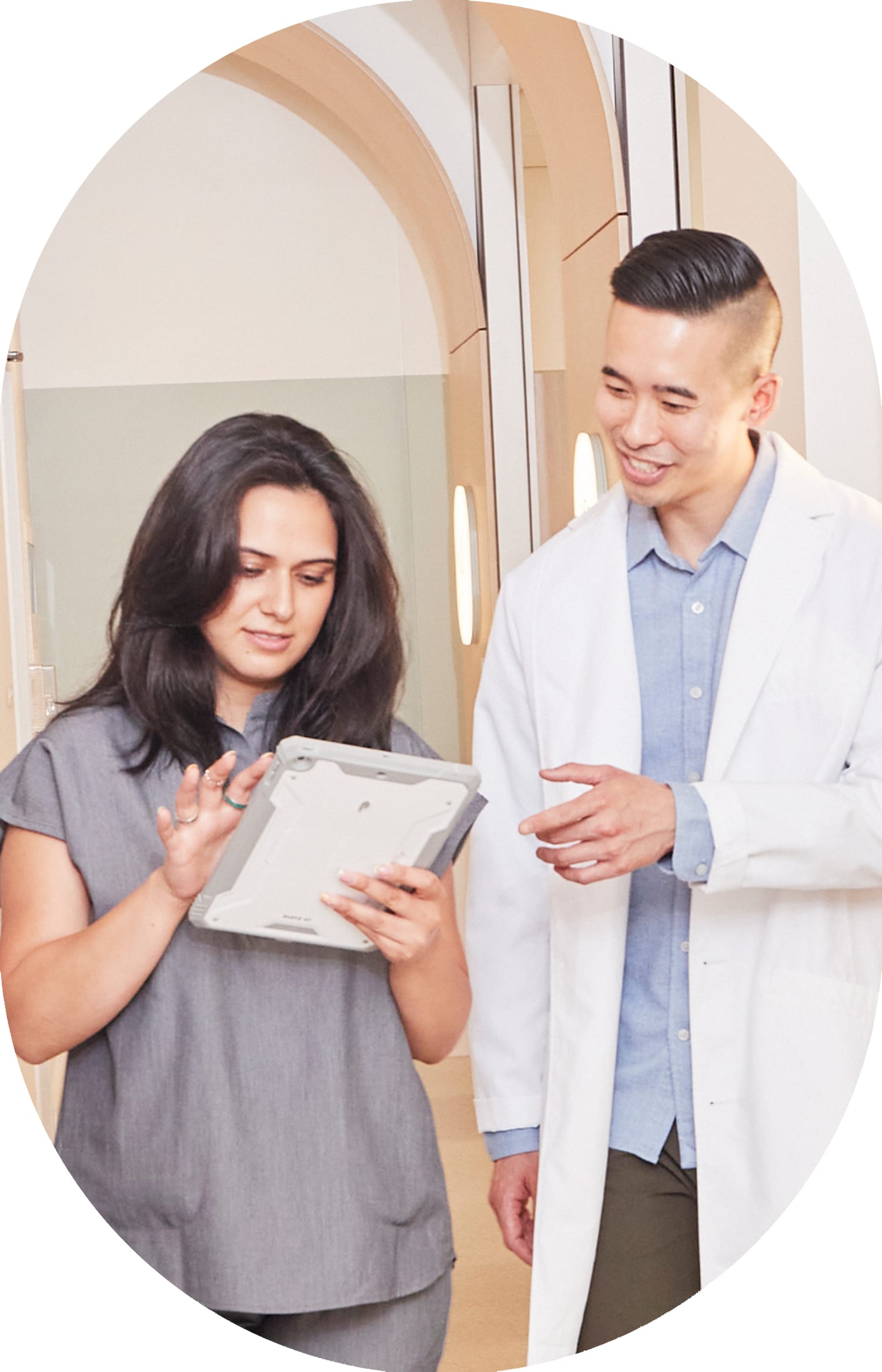 Two dental professionals from Tend Dental walk down a hallway and chat.