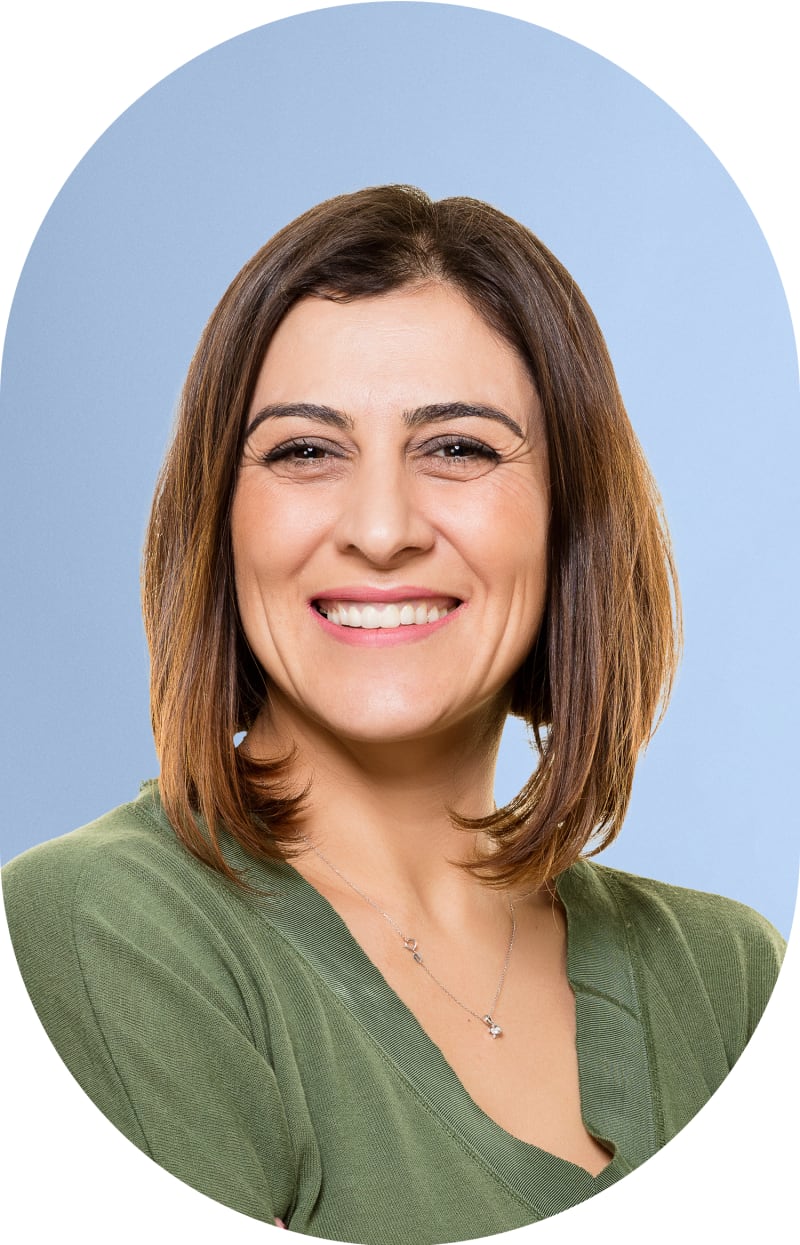 A woman in a green shirt is smiling at the camera.