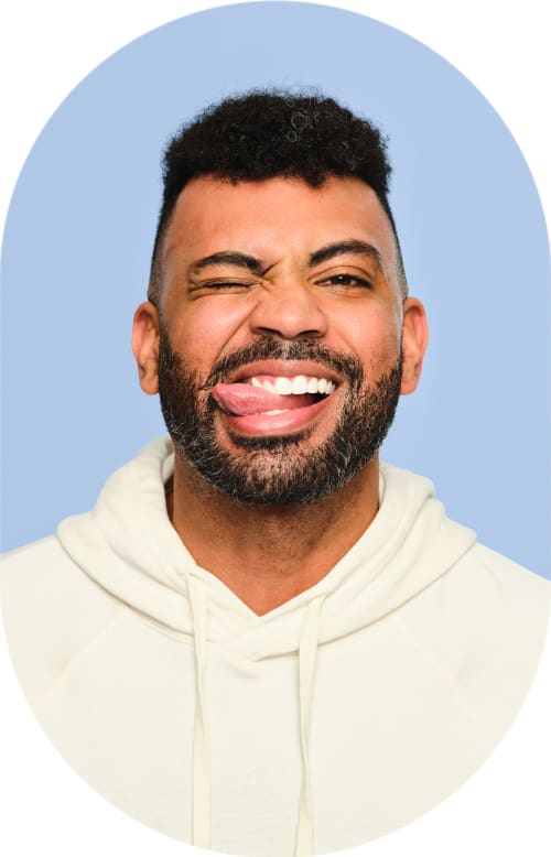 A man is smiling and scrunching up his face. He is sticking out his tongue