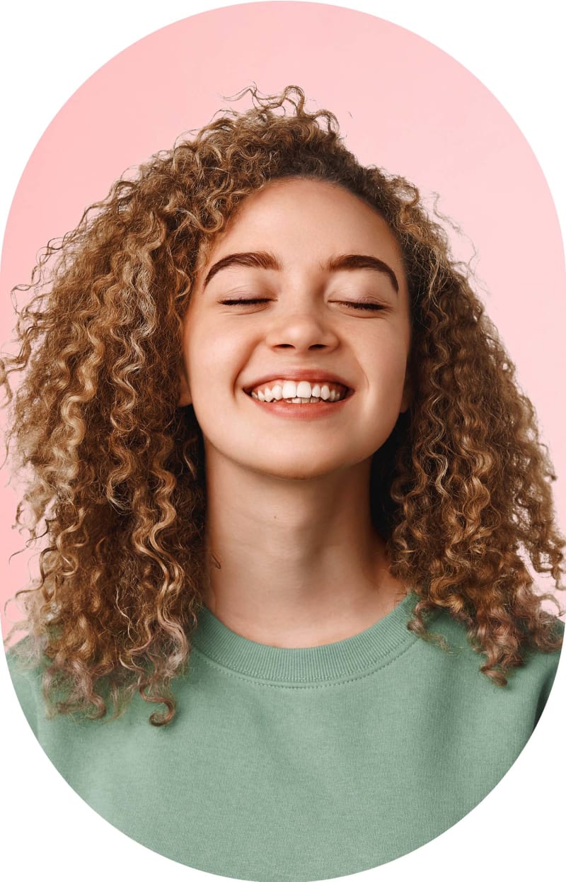 A woman with long curly hair and a big smile.