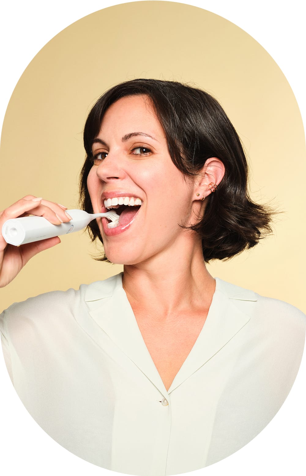 A woman is brushing her teeth with an electric toothbrush.