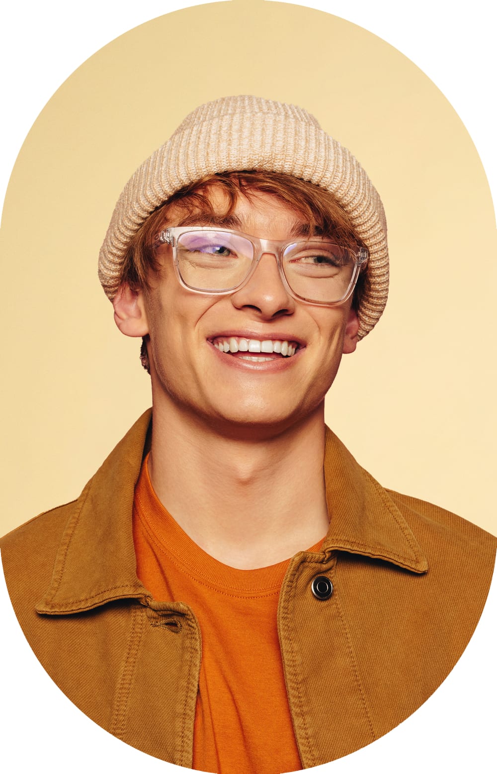 A young man with glasses and wearing a hat is smiling and looking right.