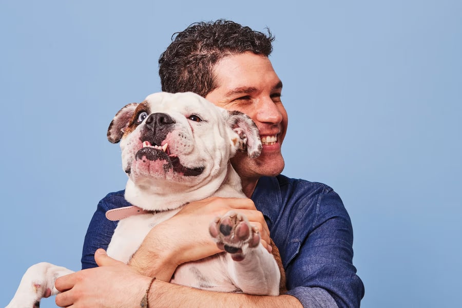 Smiling man hugging an American bulldog.