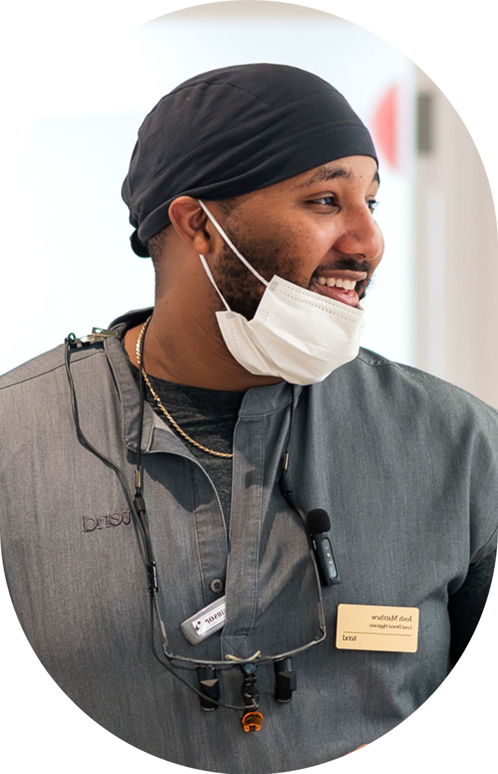 Smiling male team member is looking to his left. Below his chin is a face mask.