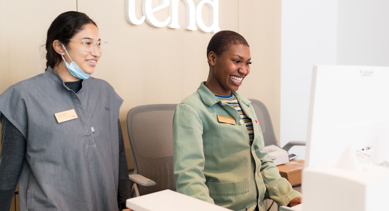 Two Tend Dental employees are smiling and looking at a computer screen.