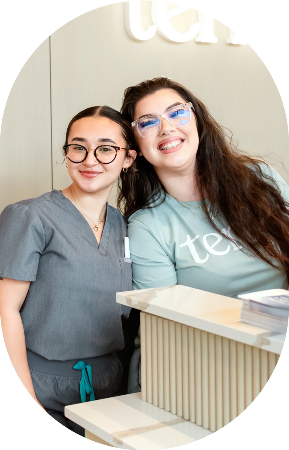Two Tend Dental employees are standing behind a counter smiling.
