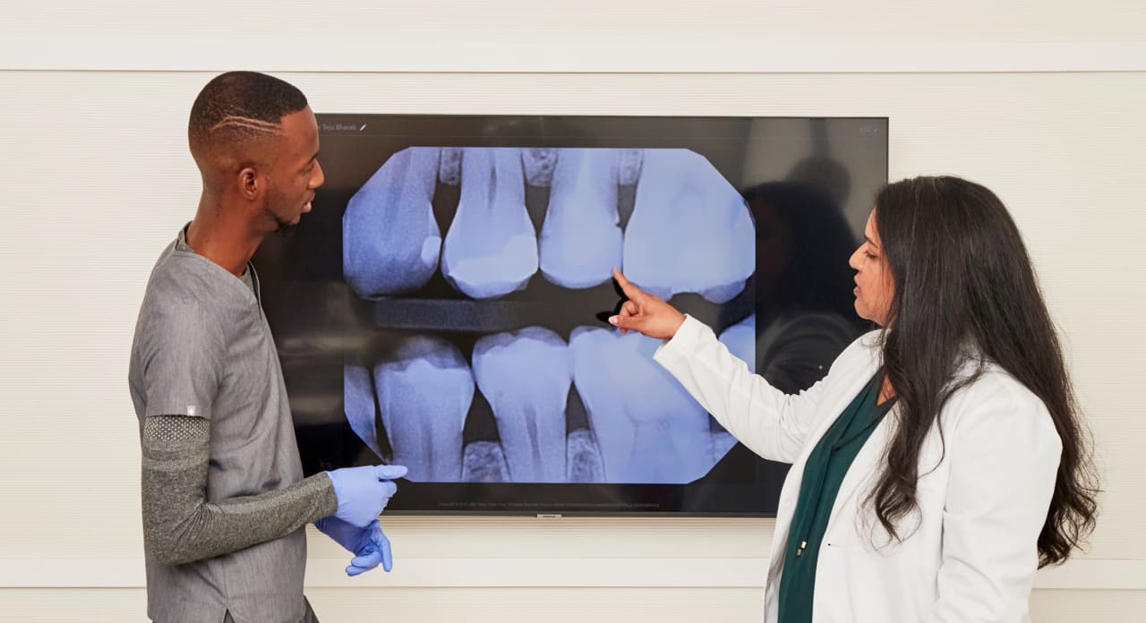 Two dental professionals from Tend Dental look at an X-ray at a large screen.