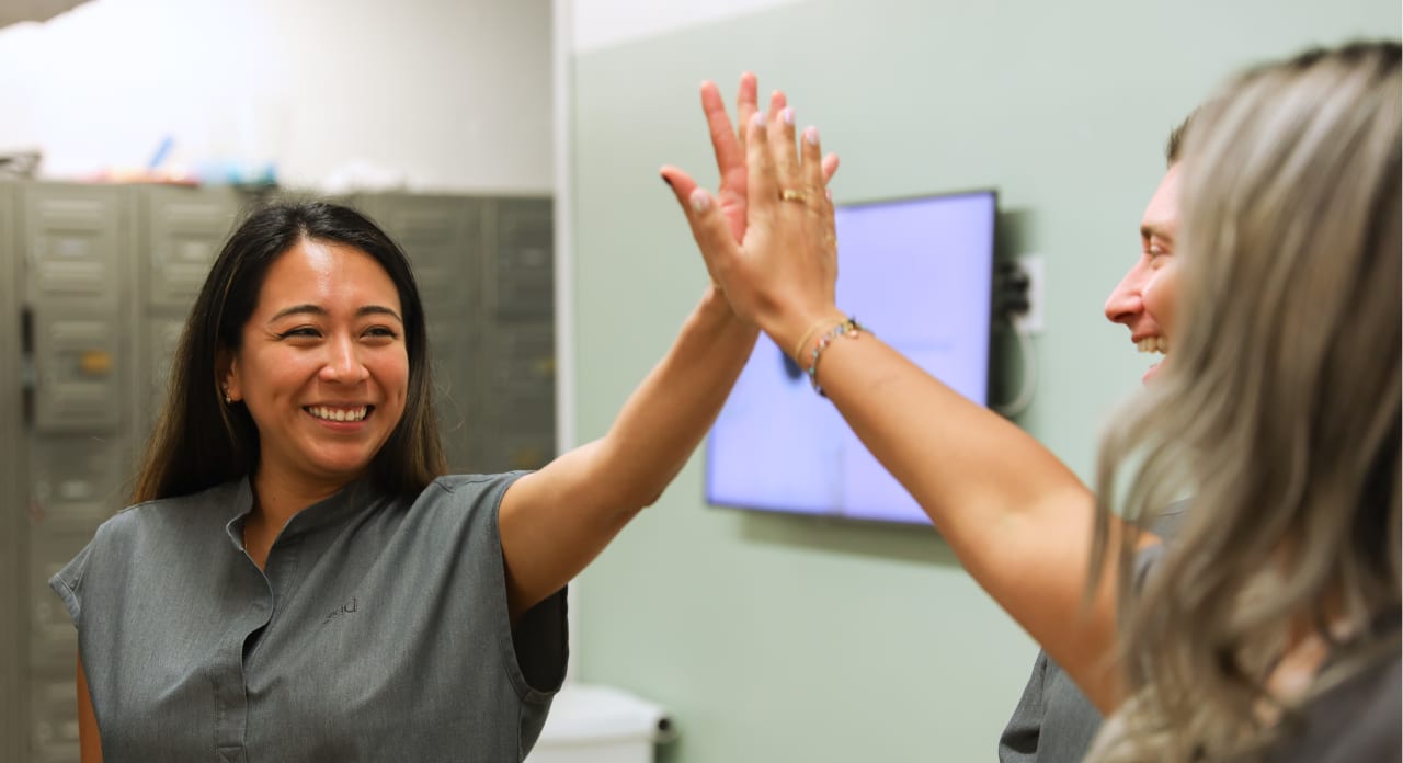Two team members from Tend Dental high five.
