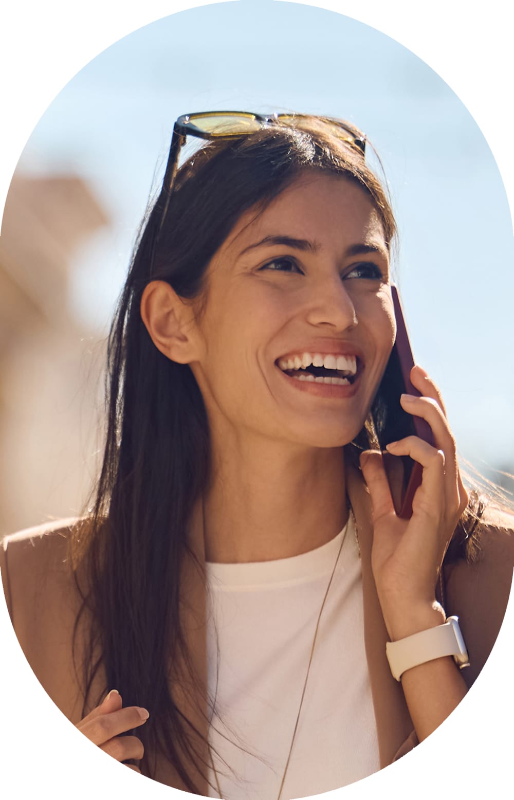 Woman stands outside smiling while wearing sunglasses.