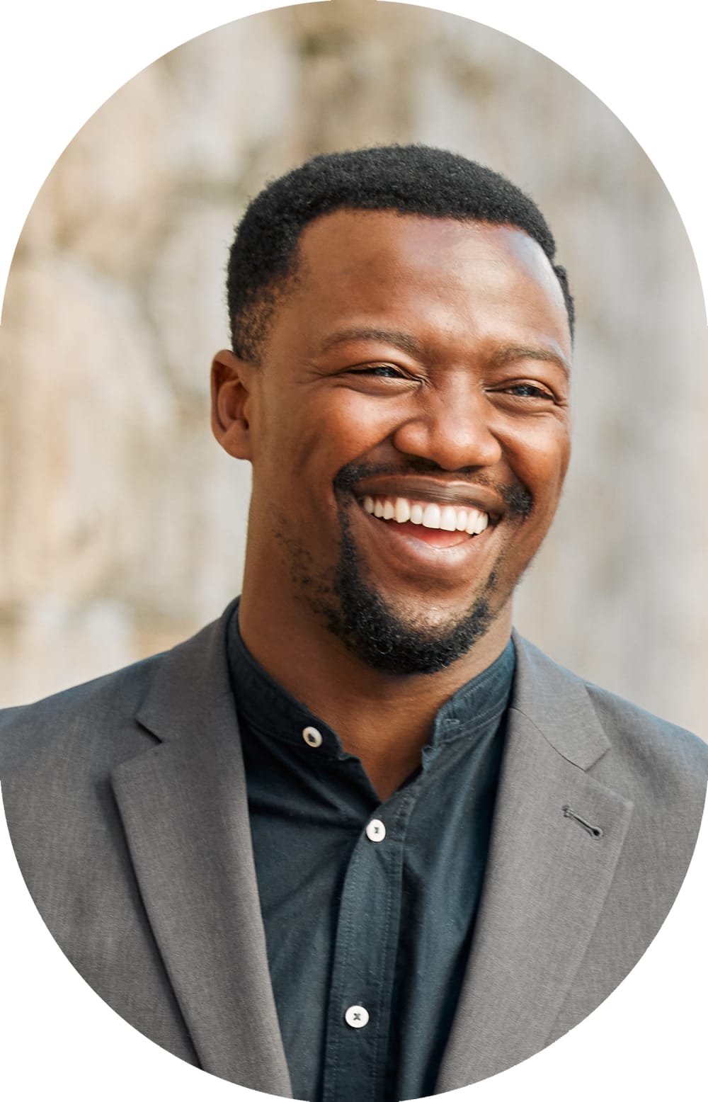Woman stands outside smiling while wearing sunglasses.
