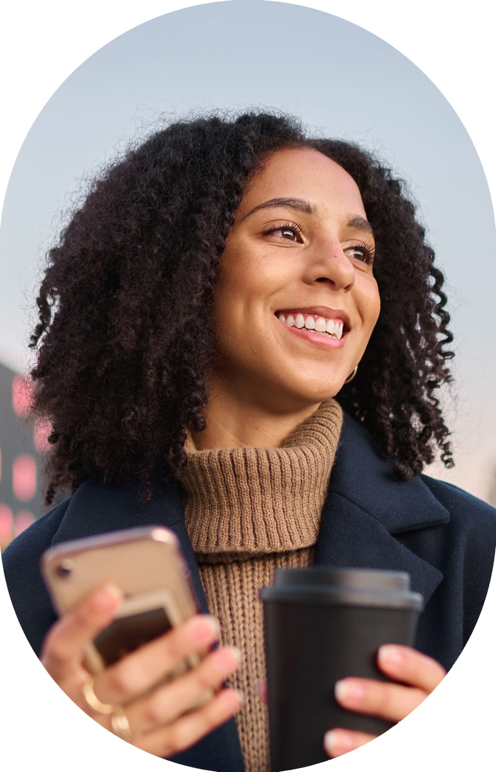 A bunsiness man with a bag strap over his shoulder stands outside smiling.