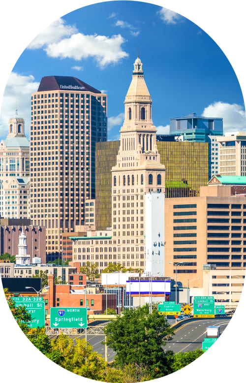 Woman stands outside smiling while wearing sunglasses.