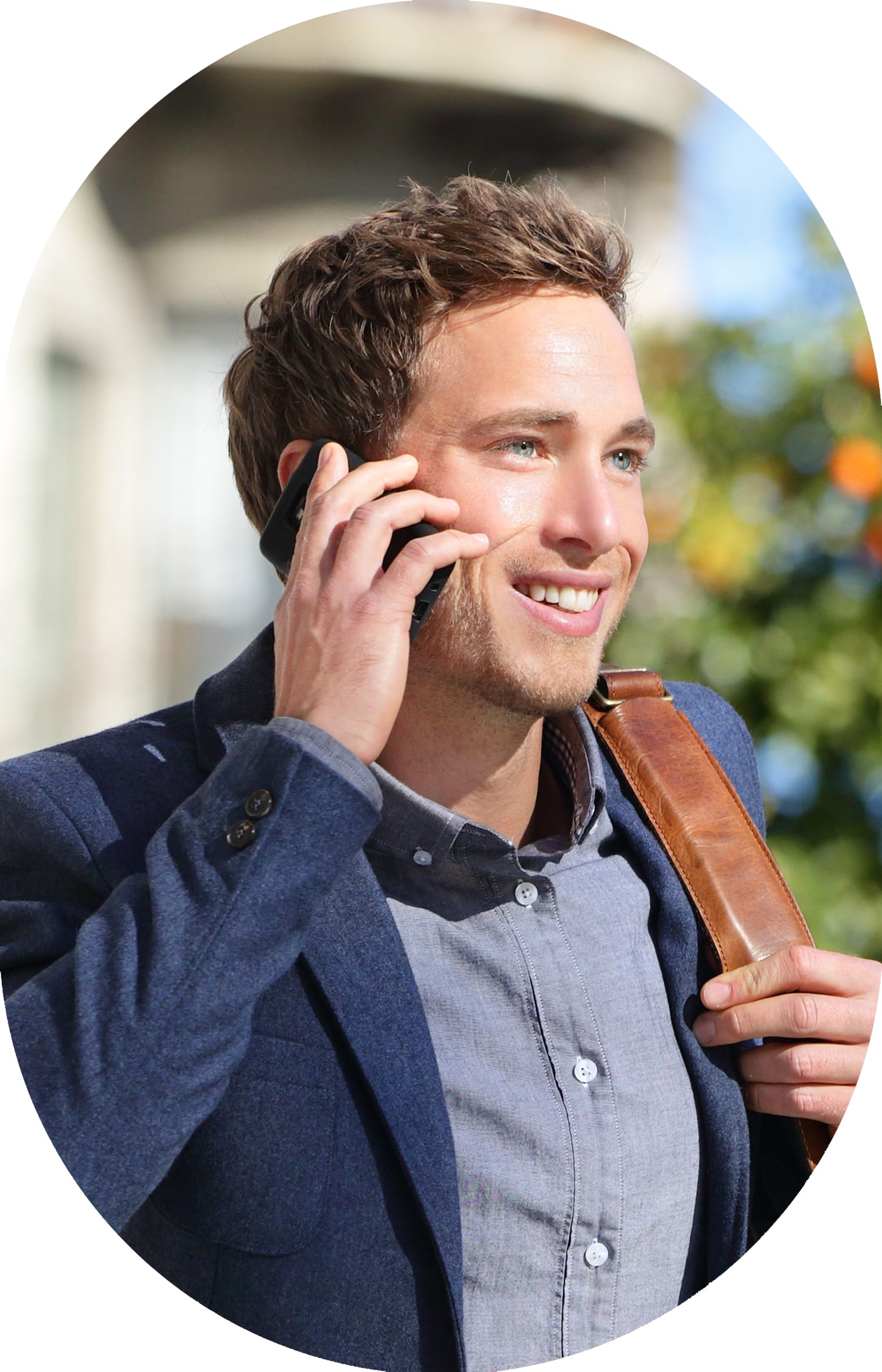 Man wearing a blue blazer walking and smiling while talking on a cellphone.