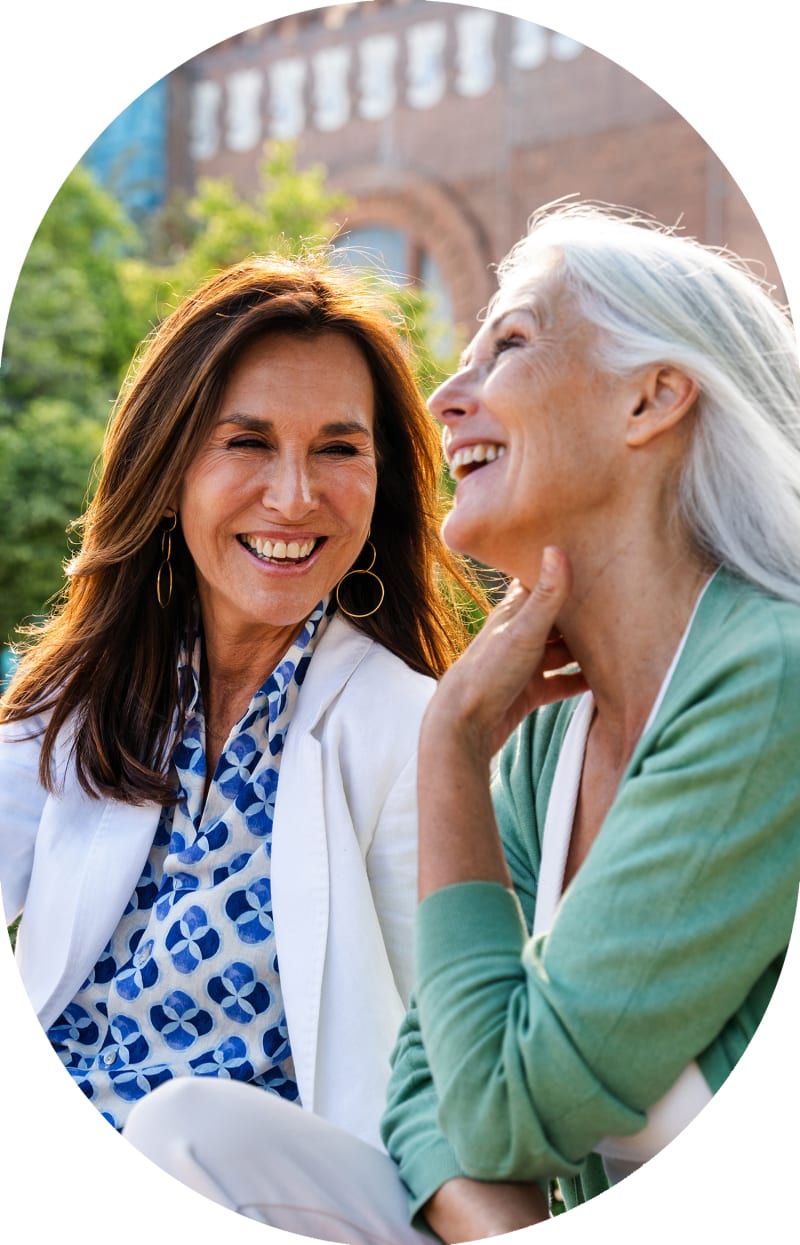 Two older women are sitting together and smiling.