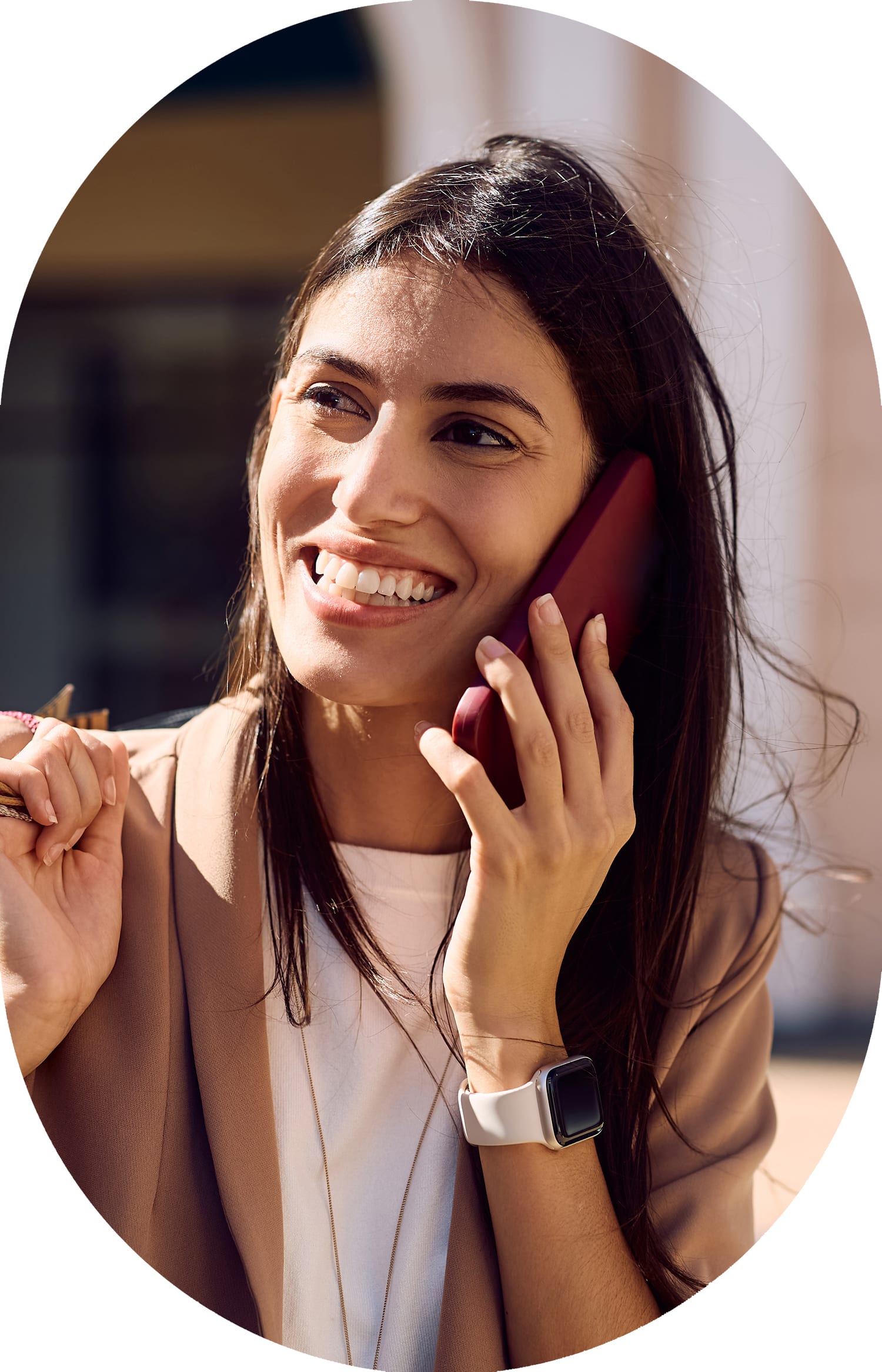 A woman wearing a tan jacket is smiling and talking on the phone.