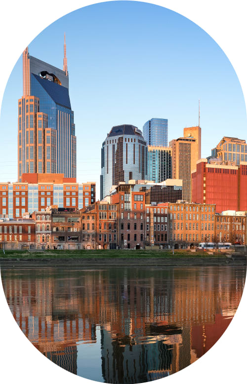 Woman stands outside smiling while wearing sunglasses.