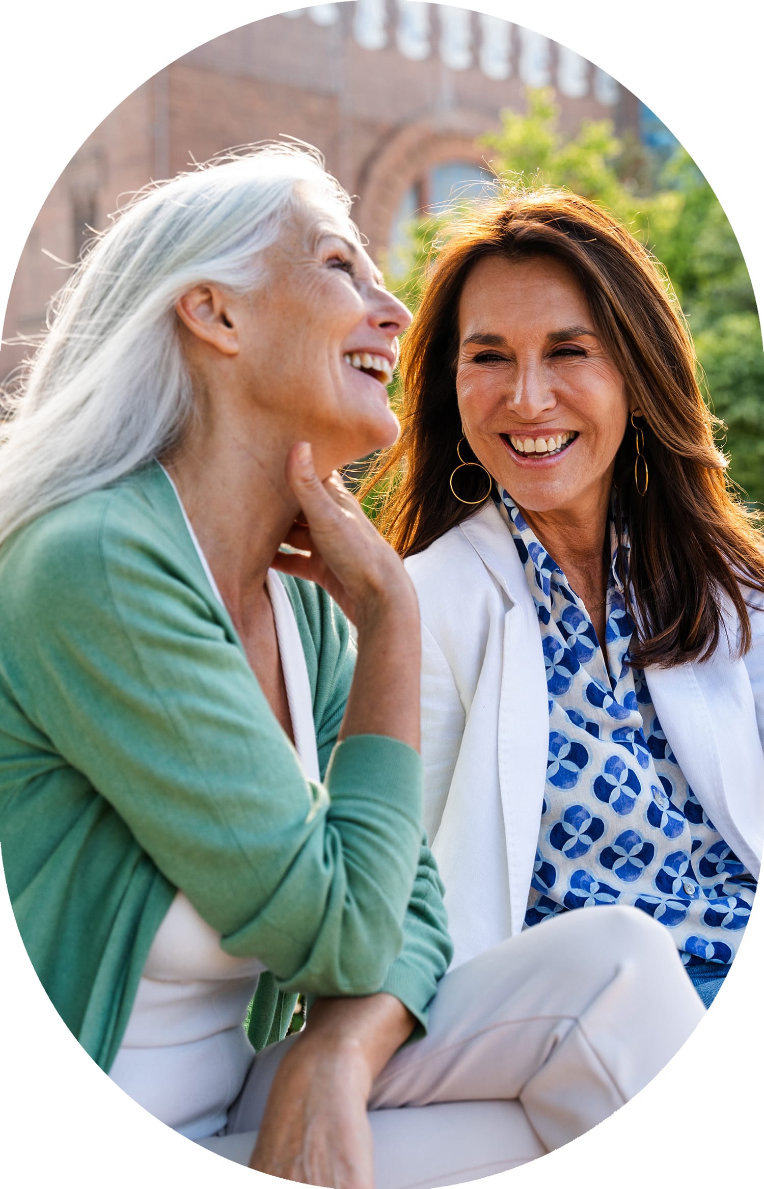Two women sitting outside smiling and laughing together