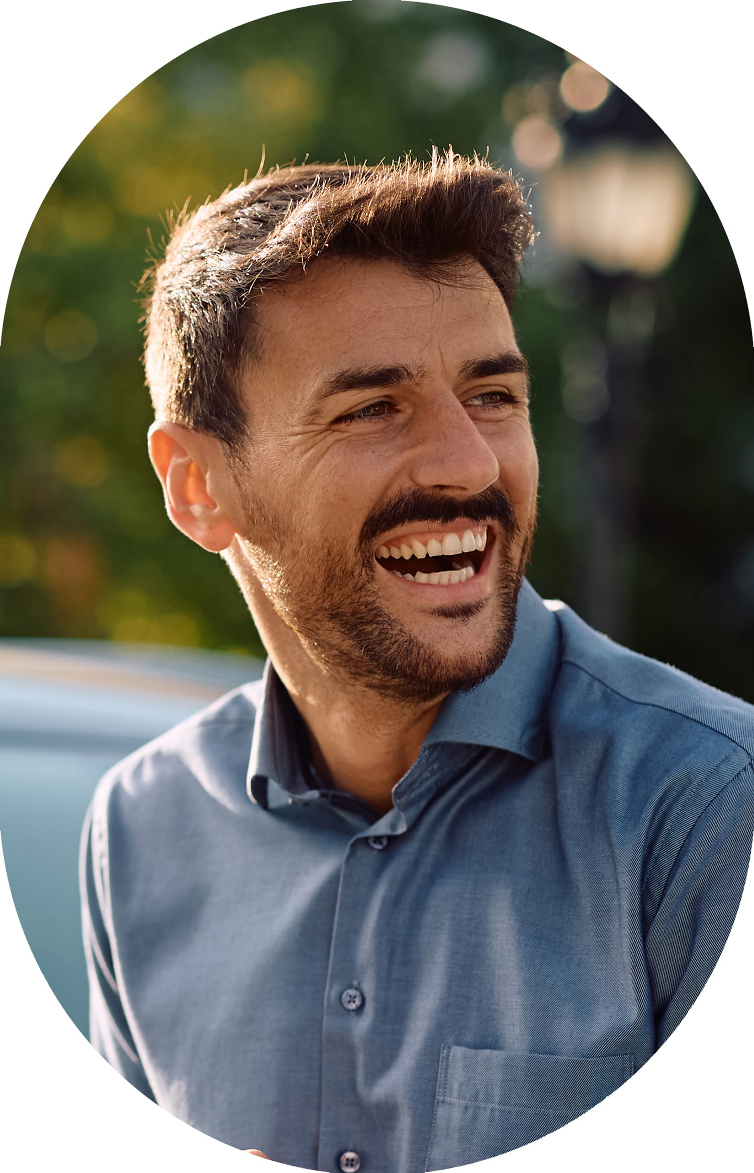 Man wearing a blue shirt, smiling while looking to the right.