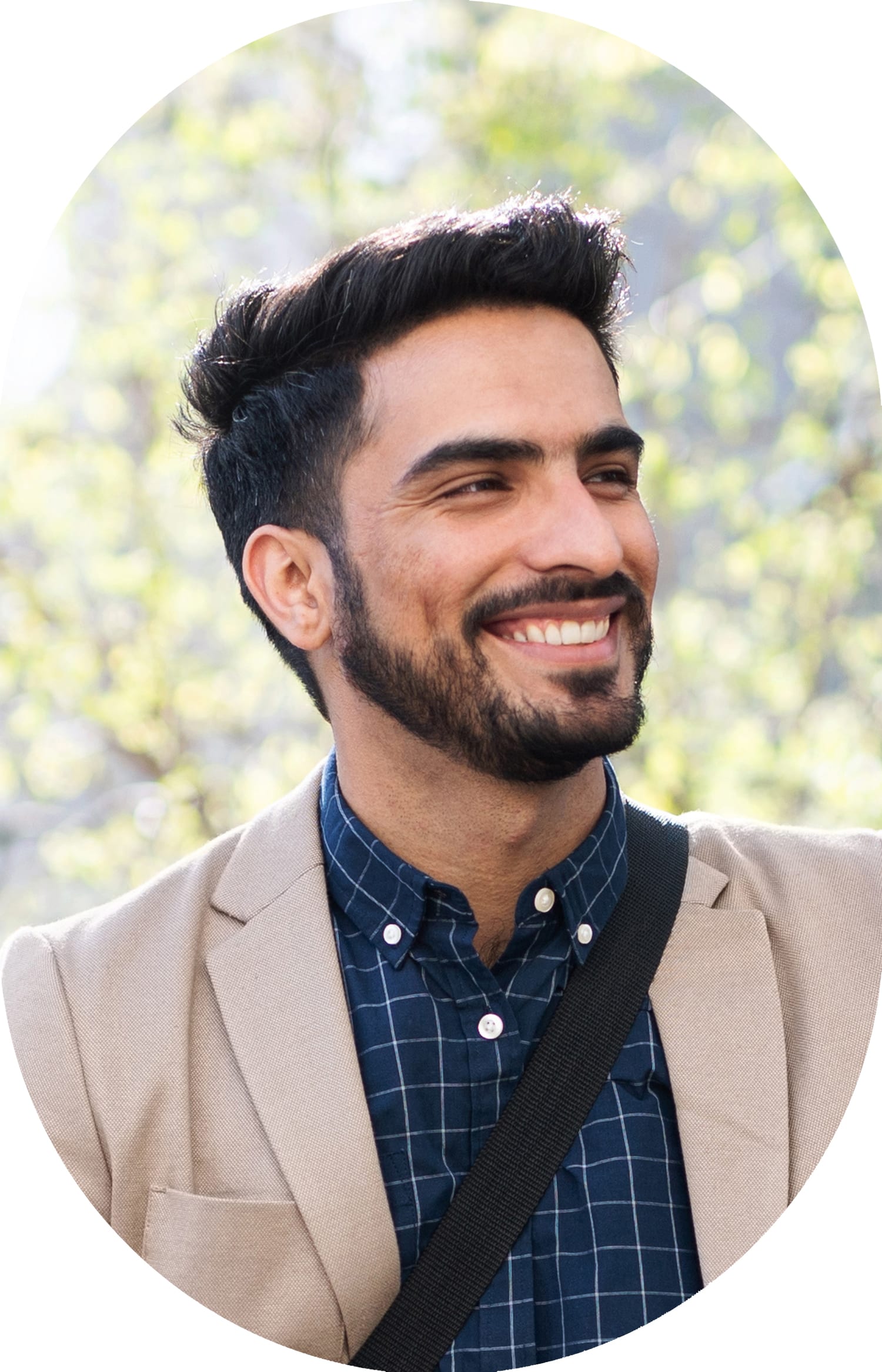 Man wearing a brown jacket, smiling while looking to the right.