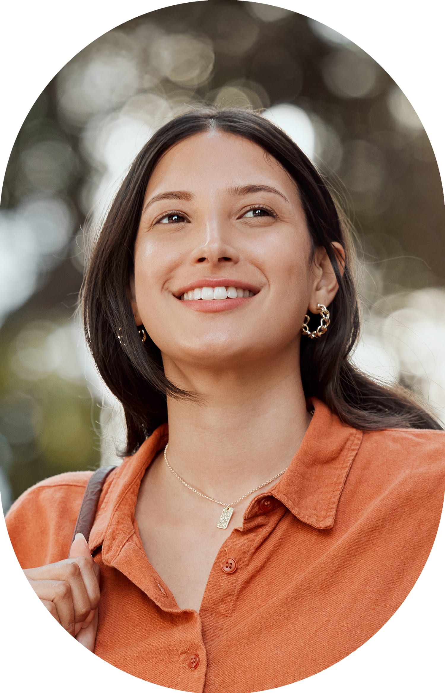 Woman wearing an orange shirt, smiling while looking to the right.
