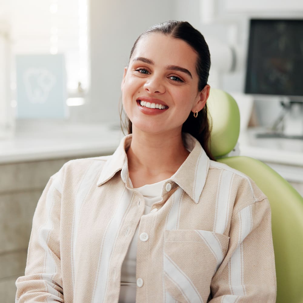 A patients sits in the treatment chair smiling.