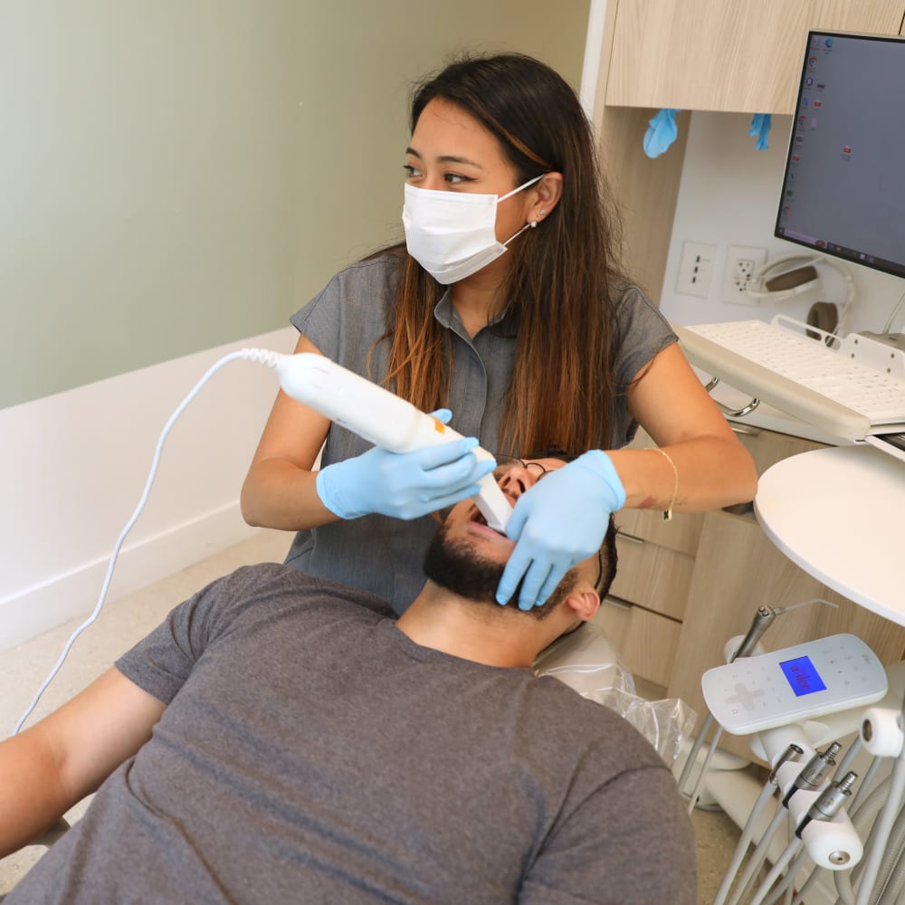 A dentist is examining a patient's mouth with an intraoral scanner.