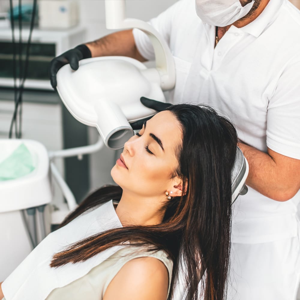 A female patient is in a dental chair about to get a dental x-ray.