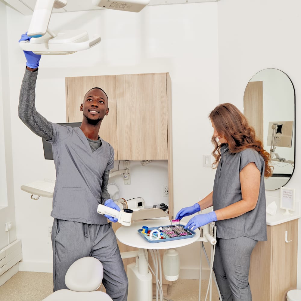Dental professionals prepare an exam room for a patient.