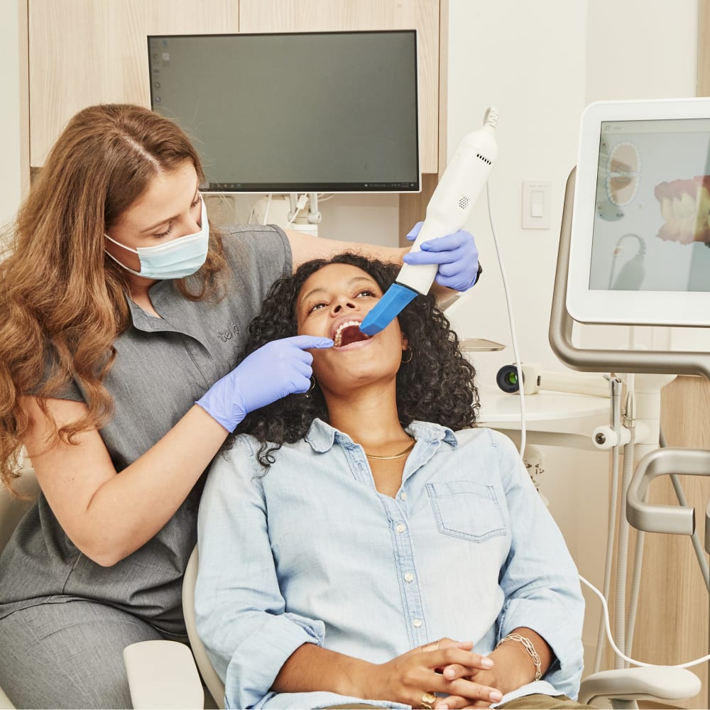 A dental professional is using an intraoral scanner to create a 3D rendering a patient's mouth.