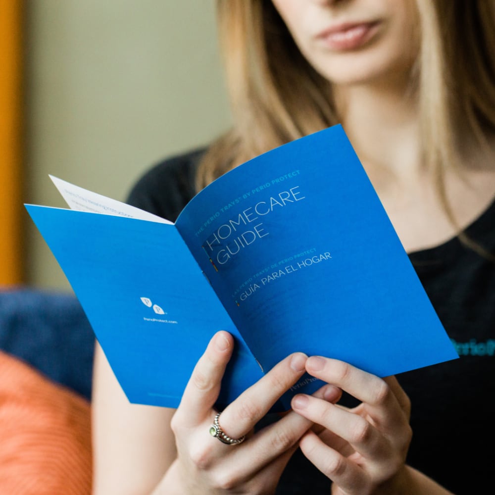 A woman reads from a Perio Protect home care manual.