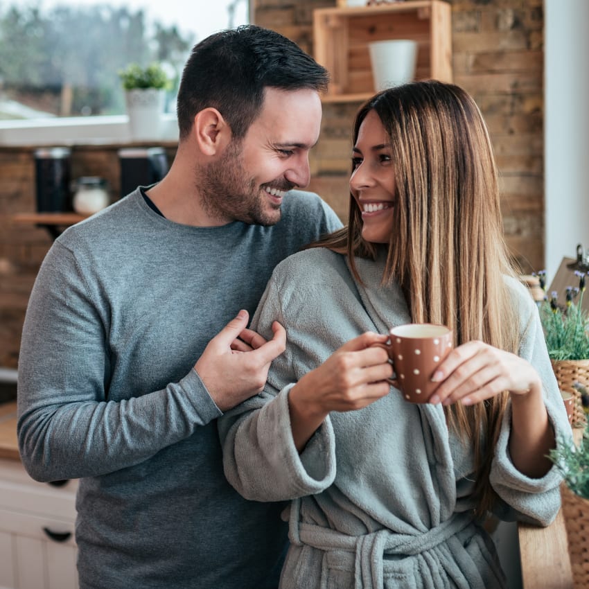 Happy couple enjoying the morning together, drinking coffee in the kitchen.